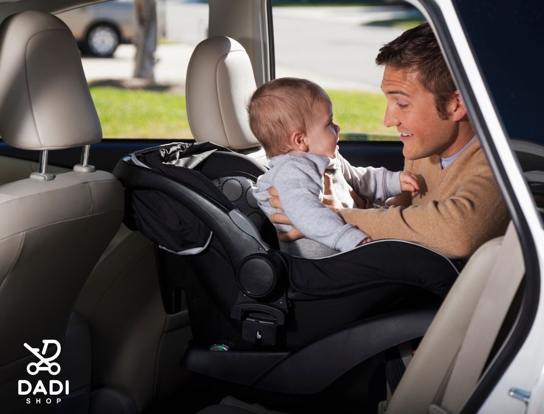 Fotelik montowany tyłem 0–13 kg z bazą ISOFIX Avionaut Dock 2 – tata bezpiecznie zapina dziecko w samochodzie.