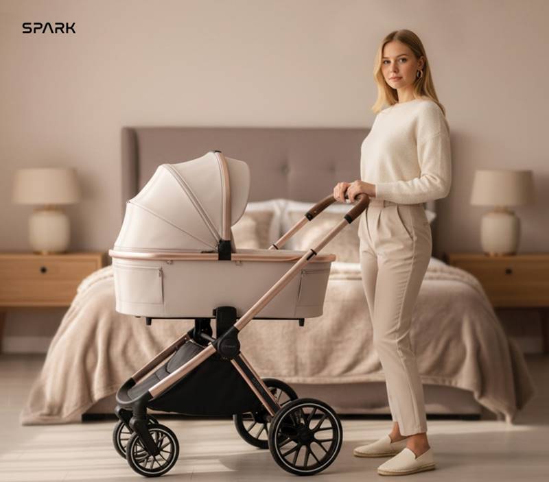 Beżowy wózek dziecięcy Adamex Spark Champagne 2w1 w sypialni – kobieta prezentuje wózek w casualowej stylizacji.