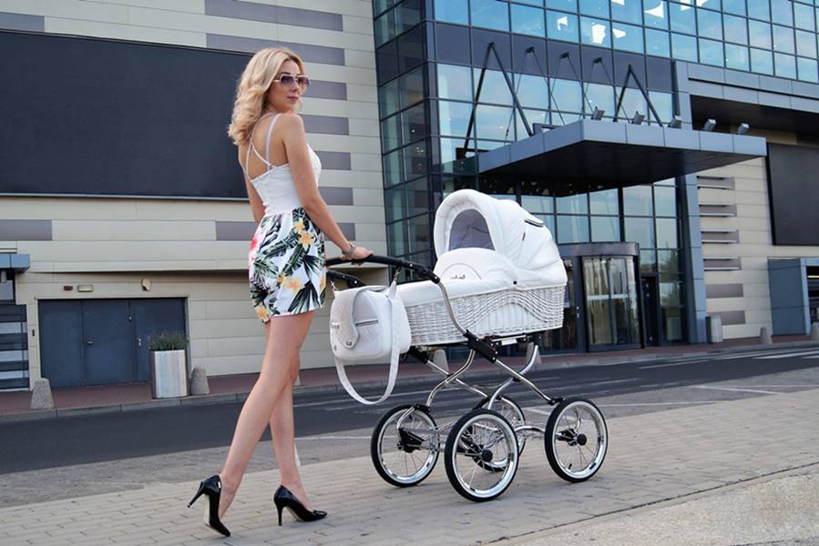 Kobieta spacerująca przy galerii handlowej z wózkiem Scarlett BW-1 na chromowanej ramie i białej tapicerce, elegancki miejski styl