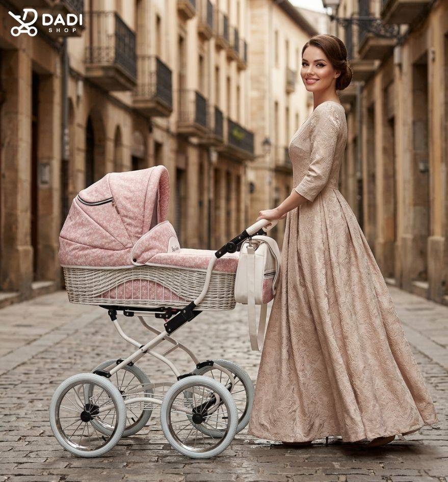 mama w vintage sukni spaceruje z wózkiem retro 3w1 Scarlett Baby Fashion w kolorze pudrowego różu z wiklinowym koszem na tle zabytkowej ulicy