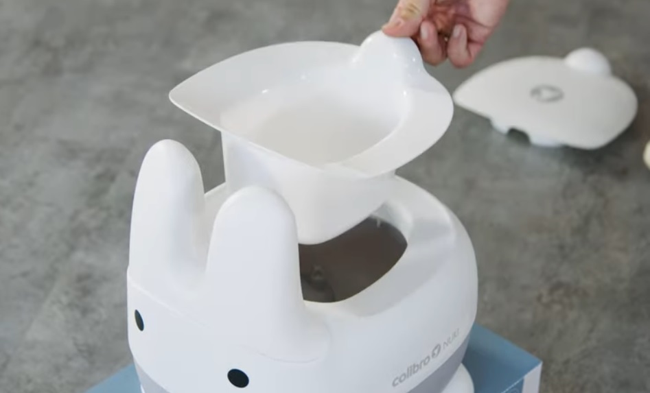 Wyjmowany wkład nocnika dziecięcego NUKI Cloud – ręka rodzica pokazuje łatwe czyszczenie i higienę nocnika.