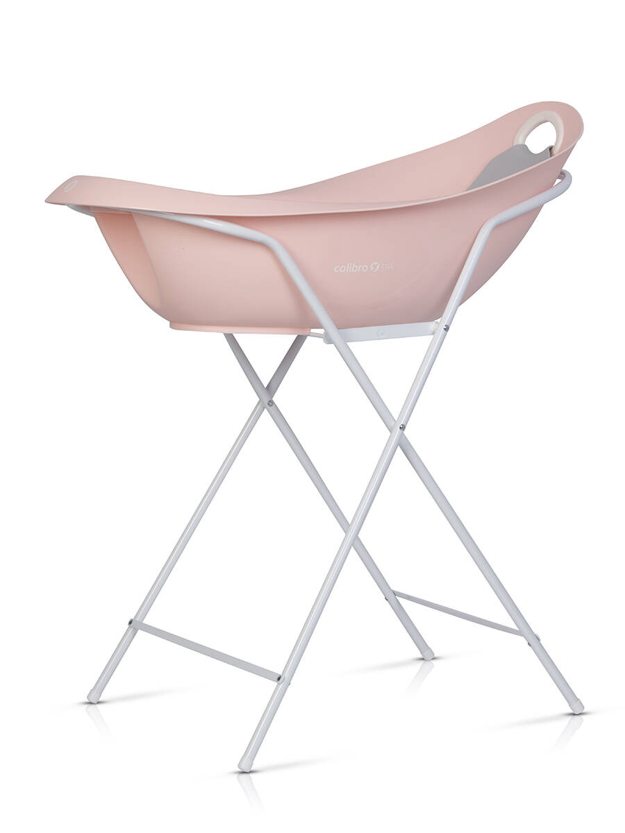 Różowa wanienka Colibro Spa na białym stelażu z widocznym szarym leżaczkiem wewnątrz. Widok pod kątem na białym tle.