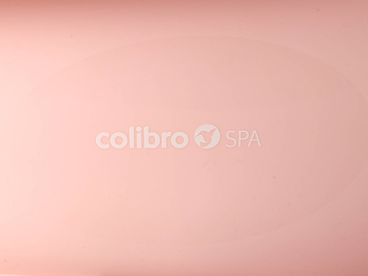 Zbliżenie na logotyp marki Colibro SPA umieszczony na różowej powierzchni wanienki.