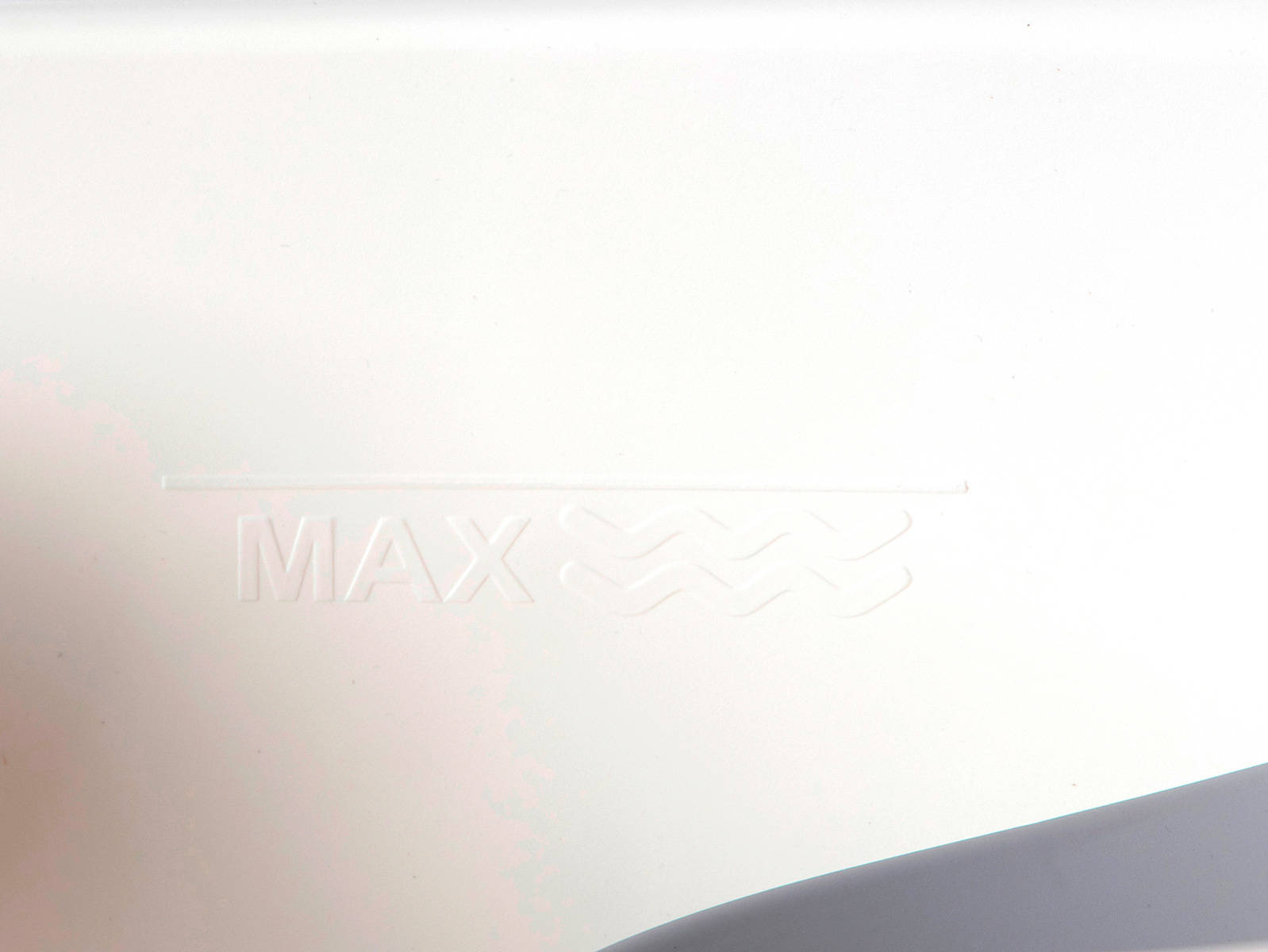 Wskaźnik maksymalnego poziomu wody wytłoczony wewnątrz białej wanienki Colibro Spa.