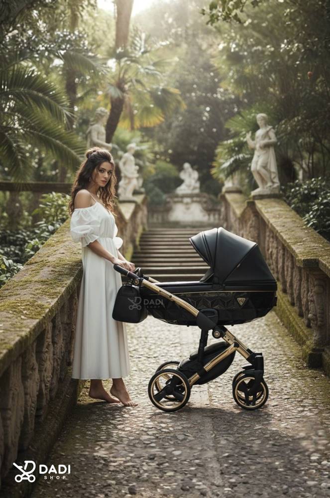 Modern black and gold Junama Fluo baby stroller with a diamond-patterned carrycot, held by a woman in a white dress in a lush, neo-classical garden setting.