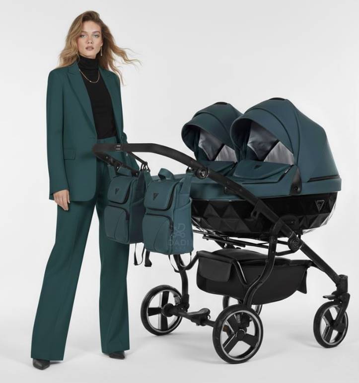 Stylowy bliźniaczy wózek Junama Basic Duo 02 butelkowa zieleń - prezentowany przez kobietę w eleganckim zielonym garniturze