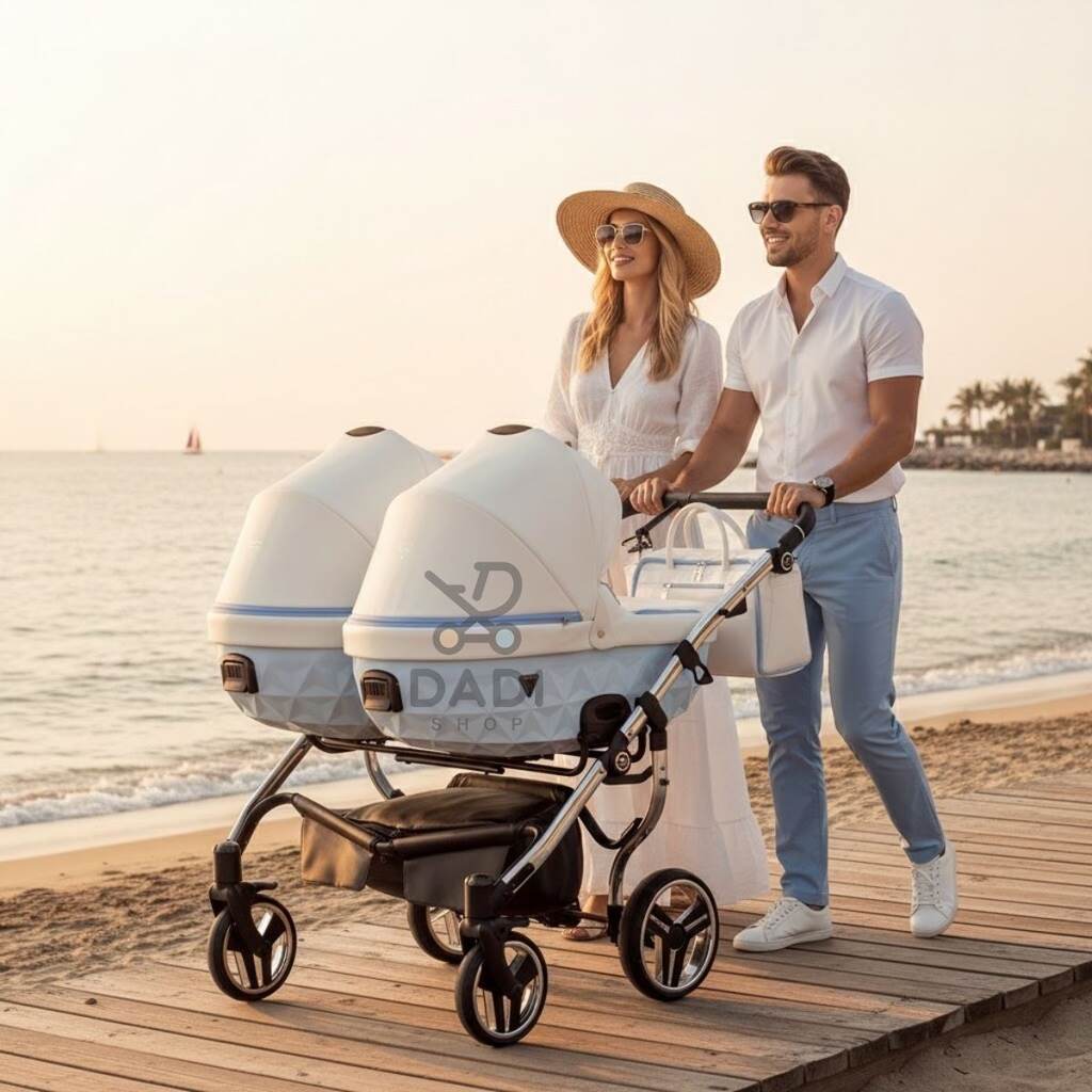 Para na plaży prowadzi niebieski wózek bliźniaczy Junama Candy Duo V2 po drewnianym podeście.