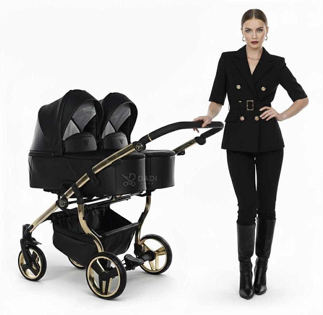 Modelka prezentuje Junama Duo V3 Eco wózek bliźniaczy w sesji studyjnej, nowoczesna konstrukcja, czarno-złota elegancja.