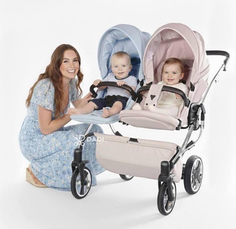 Wózek bliźniaczy Junama Duo V3 Eco – spacerówka z dwójką dzieci, chłopczyk i dziewczynka, obok kobieta.