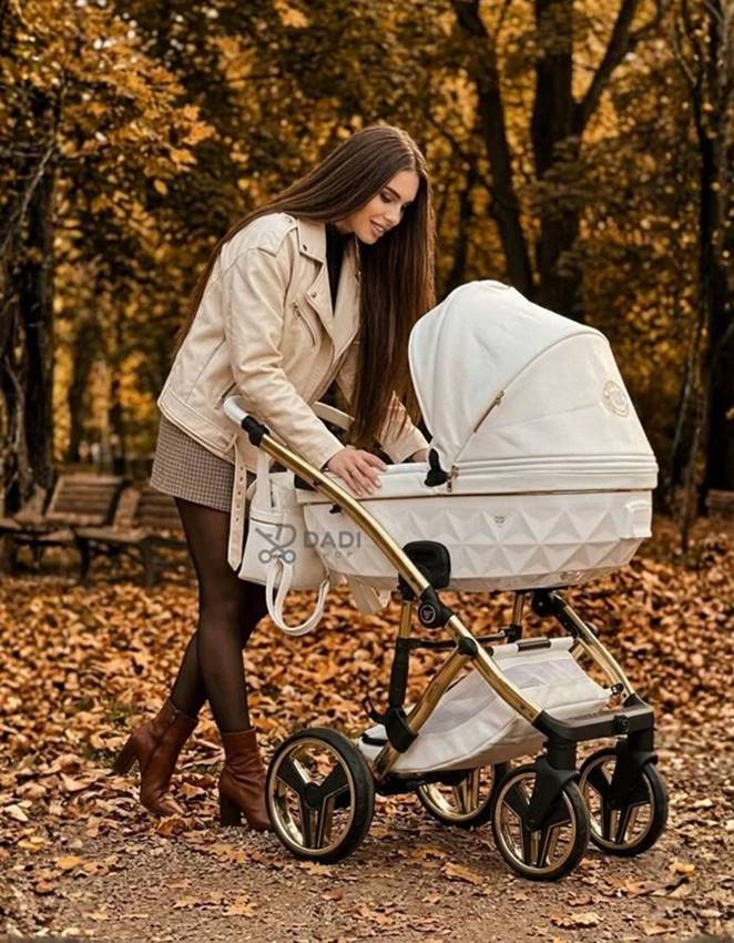Kobieta nachyla się do gondoli wózka Junama Candy Premium w kolorze białym na spacerze