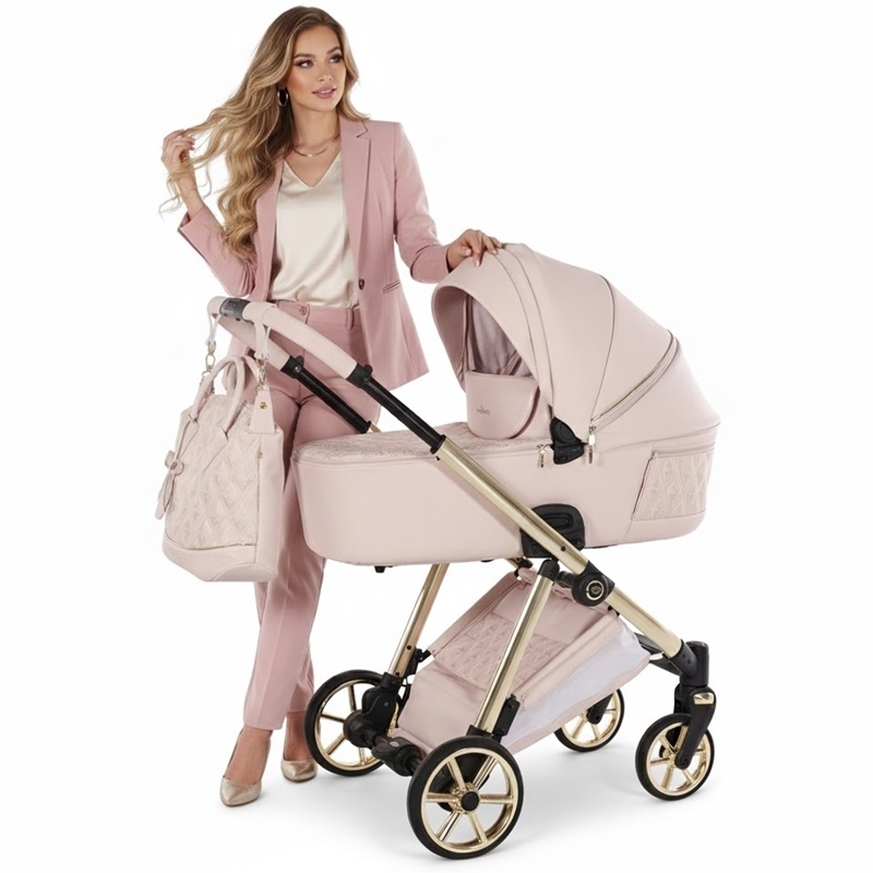 Elegancki wózek Junama Ellegante Art Deco 2w1 w pudrowym różu i złocie, prowadzony przez stylową kobietę w jasnoróżowym garniturze.