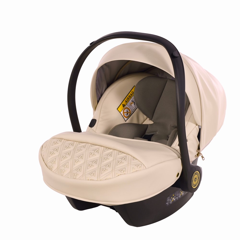 Beżowy fotelik samochodowy Junama Art Deco z pikowanym pokrowcem na nóżki, jasną budką i czarnym pałąkiem na białym tle.