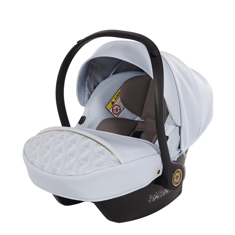 Błękitny fotelik samochodowy Junama z luksusowym wzorem Art Deco na pokrowcu. Widoczna rączka do przenoszenia i miękka wkładka dla niemowlęcia.