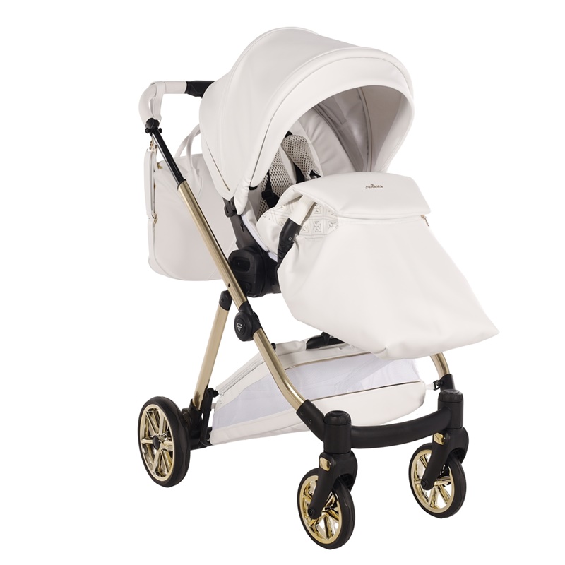 Biała spacerówka Junama Ellegante Art Deco 04 ze złotym stelażem i założonym pokrowcem na nóżki. Widoczna biała torba.