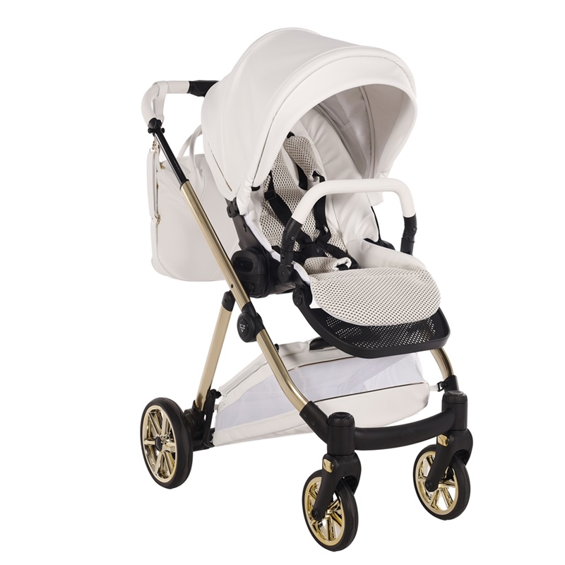 Biała spacerówka Junama Ellegante Art Deco 04 na złotym stelażu. Widok na jasną wkładkę, pasy bezpieczeństwa i dolny kosz.