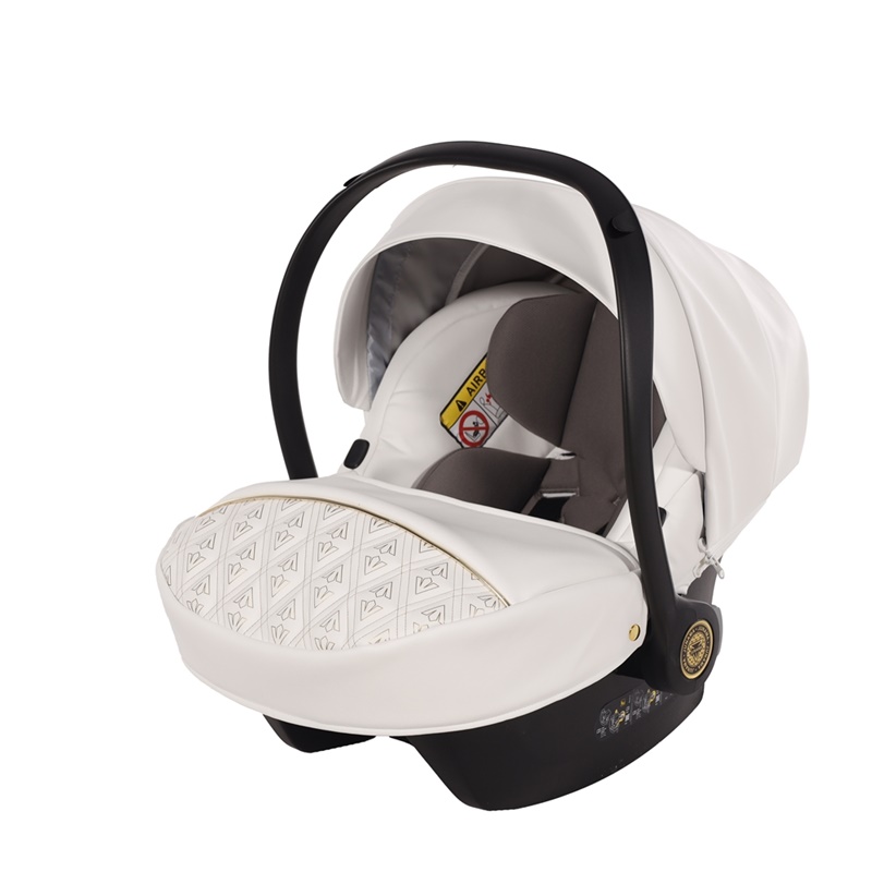 Biały fotelik samochodowy Junama Ellegante Art Deco 04 z geometrycznym wzorem na pokrowcu i czarnym pałąkiem.