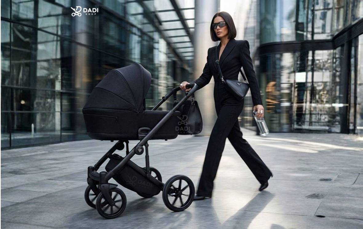 Kobieta spaceruje z wózkiem Junama Ellegante Termo 04 Black w nowoczesnym miejskim otoczeniu.