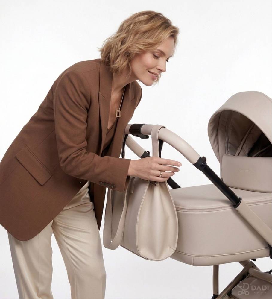 Junama Termo Ellegante 2w1 Light Beige – kobieta z torbą przy eleganckim wózku dziecięcym z gondolą.