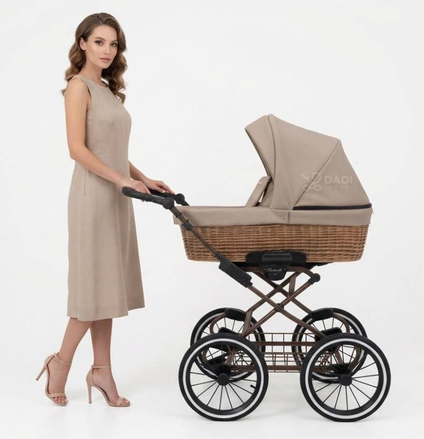 wózek retro 4w1 Kunert Romantic Classic w odcieniu latte z naturalną wikliną, pchany przez modelkę w eleganckiej stylizacji. Widoczna charakterystyczna rama i duże szprychowe koła.