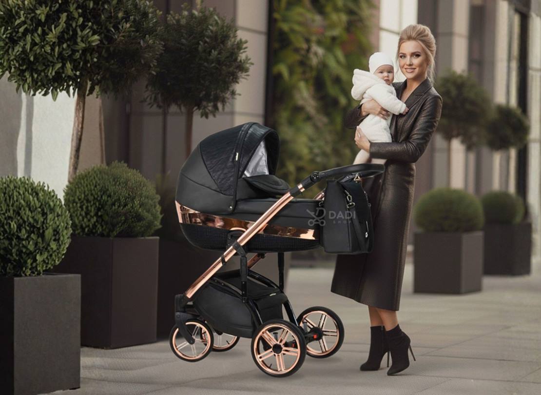 Wózek dziecięcy Wiejar Monte Negro w czarno miedzianym kolorze. Sesja miejska: elegancka mama trzyma niemowlę obok wózka.