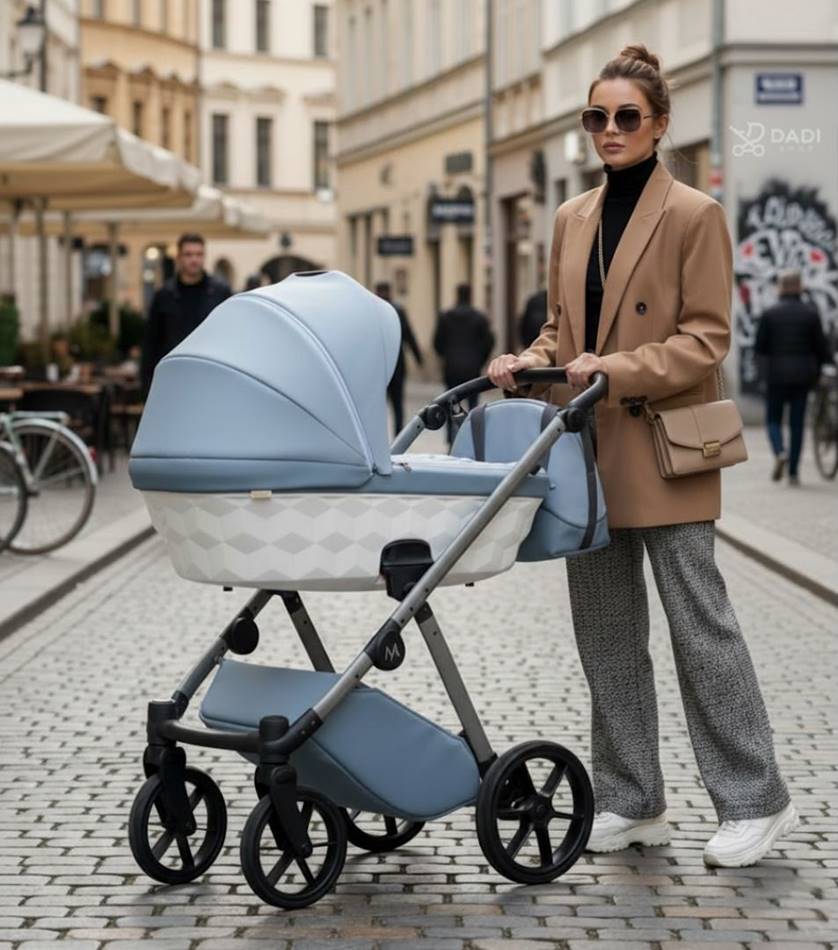 Modne zdjęcie typu street style: kobieta w beżowym płaszczu prowadzi wózek Natoni Baby Abis w kolorze powder blue po brukowanej ulicy. Zdjęcie podkreśla nowoczesny design wózka i styl życia.