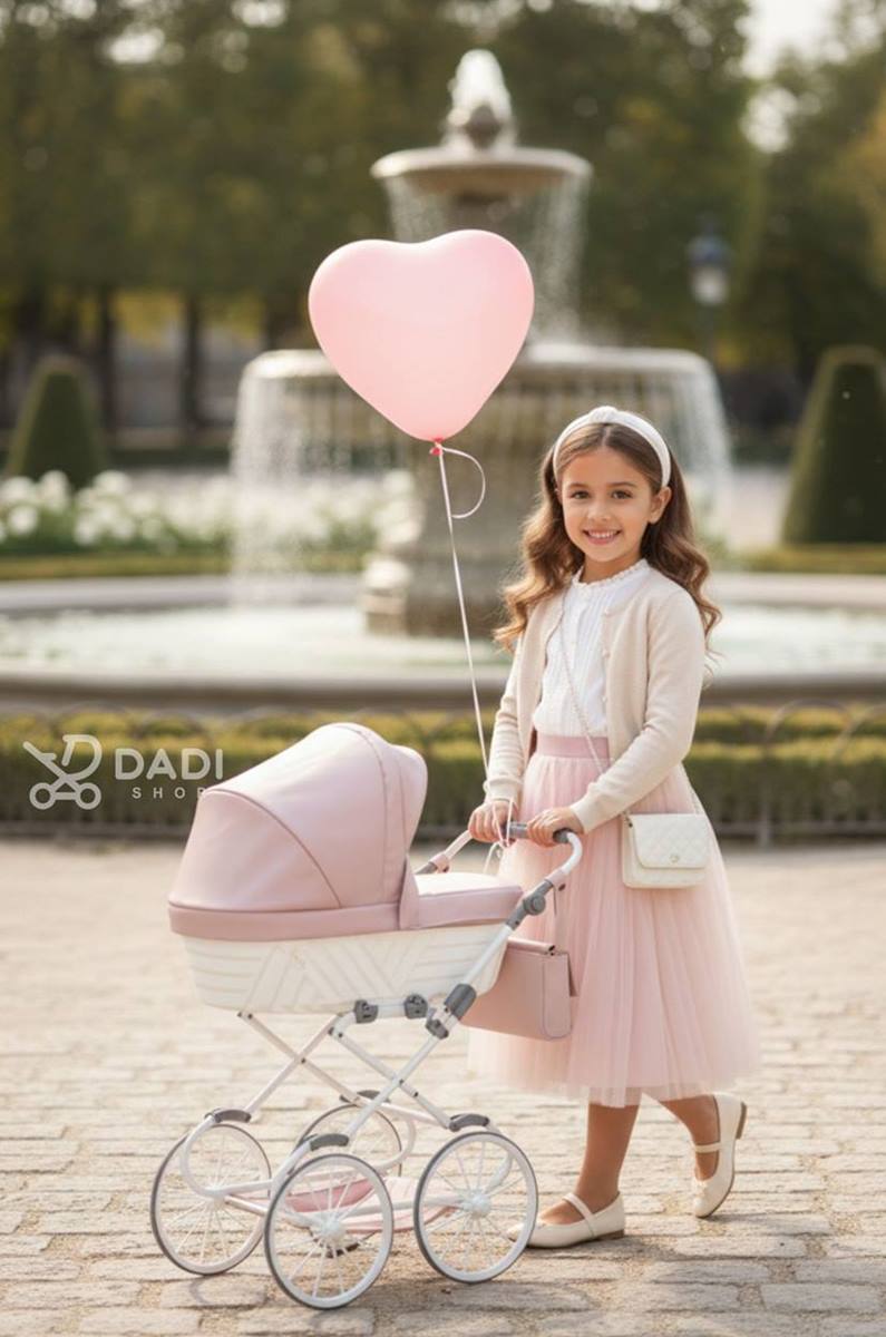 Wózek dla lalek Kunert Rossie – 6-latka prowadzi wózek przy fontannie, stylowa zabawka lalkowa. Dadi-shop