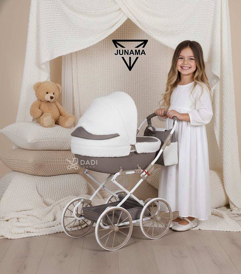 Girl presenting Junama Mocha Dream Mini beige doll stroller during a cozy, comfy studio session.