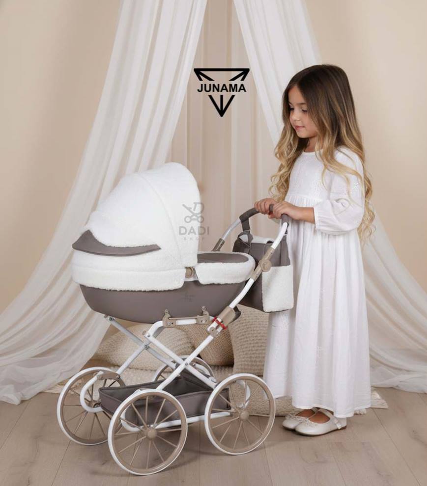 Sesja w studio: dziewczynka ogląda wnętrze wózka dla lalek Junama Mocha Dream Mini, widoczne detale tkaniny bouclé na budce.