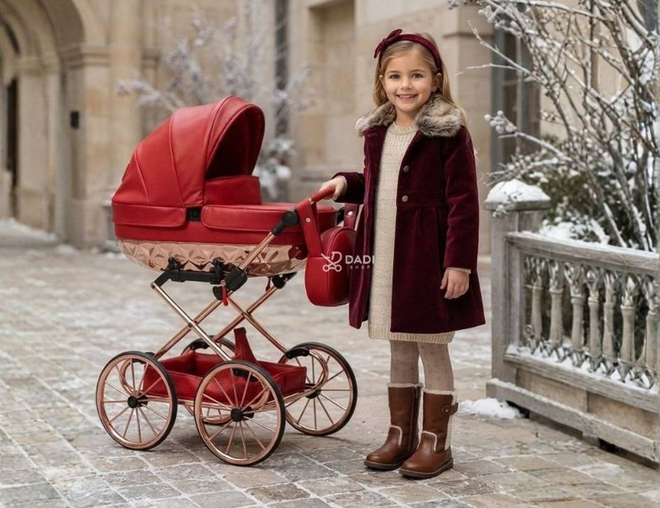 Luxury red doll doll pram Junama Rudolf with a gold chassis and a stylish little girl in a winter outdoor setting.